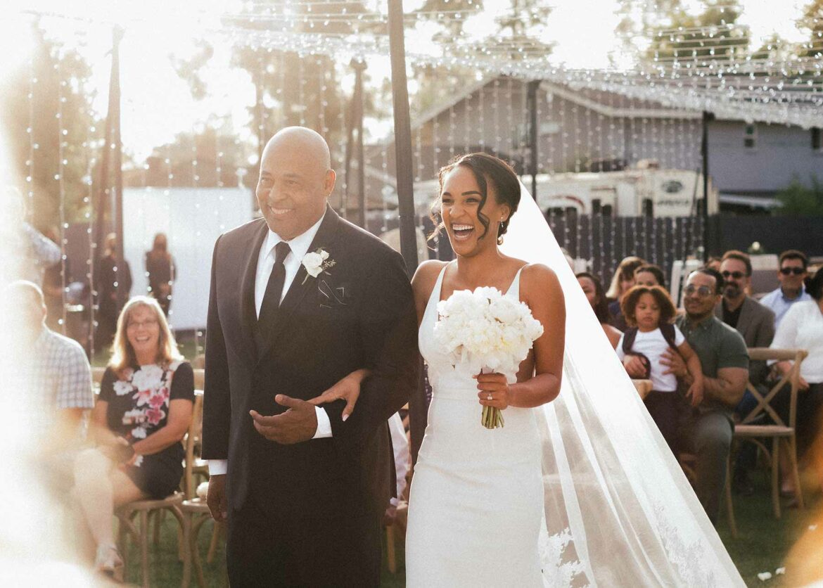 A bride walks down the aisle with her father during a wedding processional