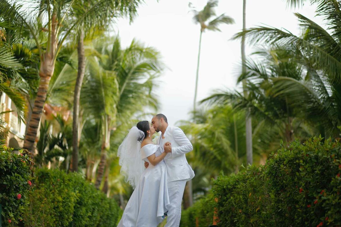 A couple embracing with tropical trees in the background of their destination wedding